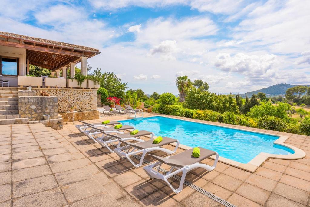 a villa with a swimming pool and lounge chairs at Es Bosquet in Inca