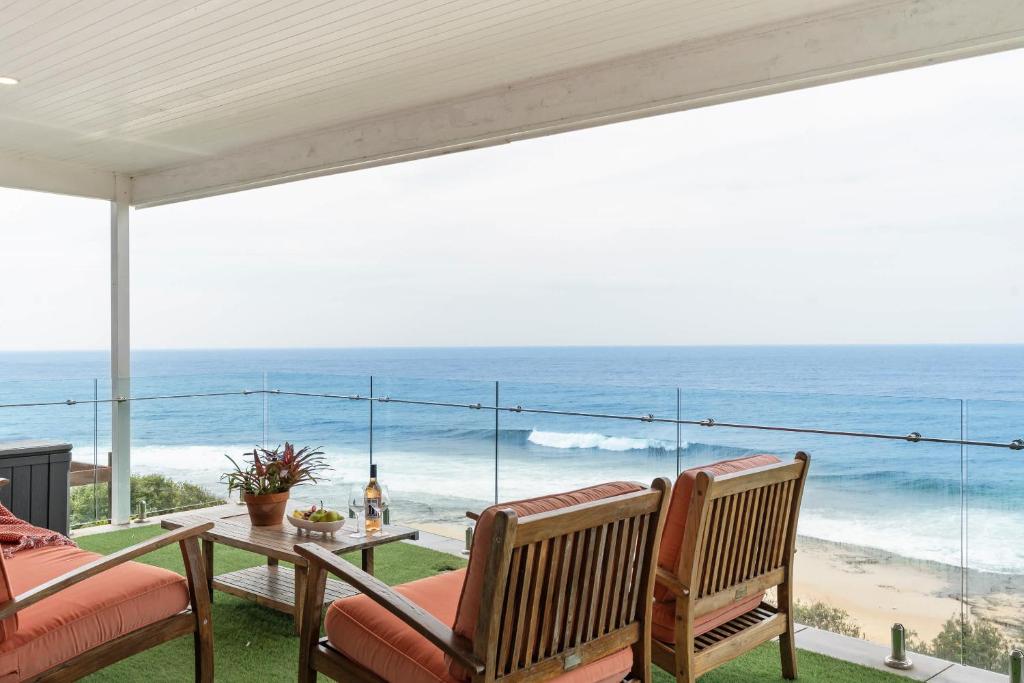 a patio with a table and chairs and the ocean at Flatrock Penthouse Ulladulla in Ulladulla