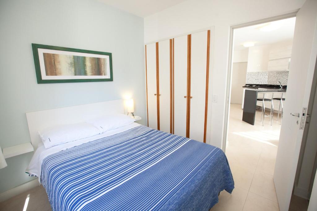 een slaapkamer met een bed met een blauw en wit gestreepte deken bij Oscar Freire Apart in Sao Paulo