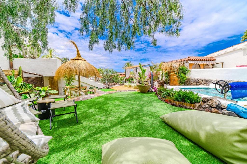 a backyard with a green lawn and a swimming pool at Oceania Villa Private Pool Garden in Chayofa