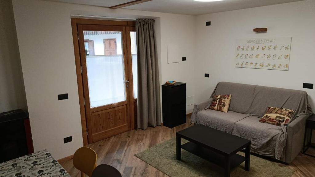 a living room with a couch and a door at Appartamento Via Livigno in Isolaccia