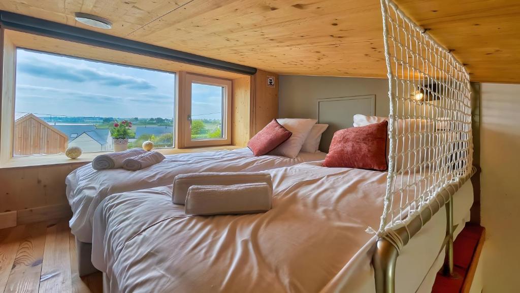 un grand lit dans une chambre avec une grande fenêtre dans l'établissement La villa Grand Ouest, à Plounéour-Trez
