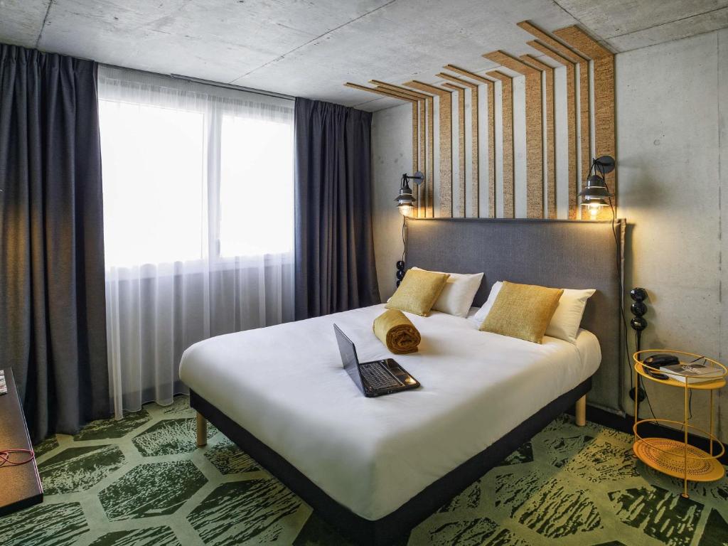 a bedroom with a large bed with a laptop on it at ibis Styles Amiens Centre in Amiens