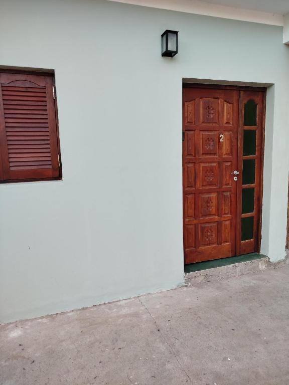 a white building with a wooden door and a window at Monoambiente Para 2 in Belén