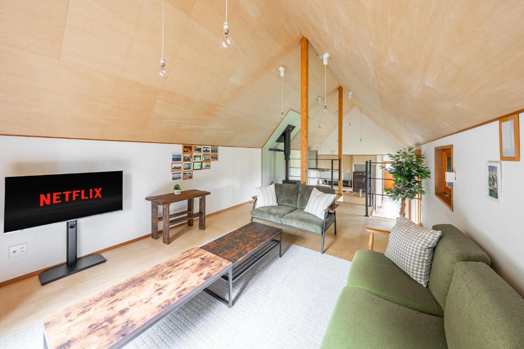 a living room with a couch and a tv at Poroto House in Nanae