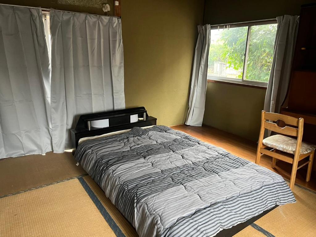 a bedroom with a bed and a chair and a window at 九州 福岡 貸切 プライベートハウス 