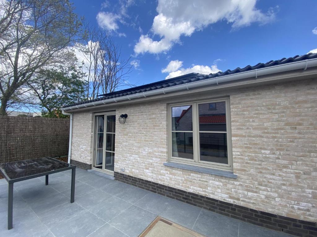 una casa de ladrillo con un banco en el patio en Westhinder II H52, en Koksijde