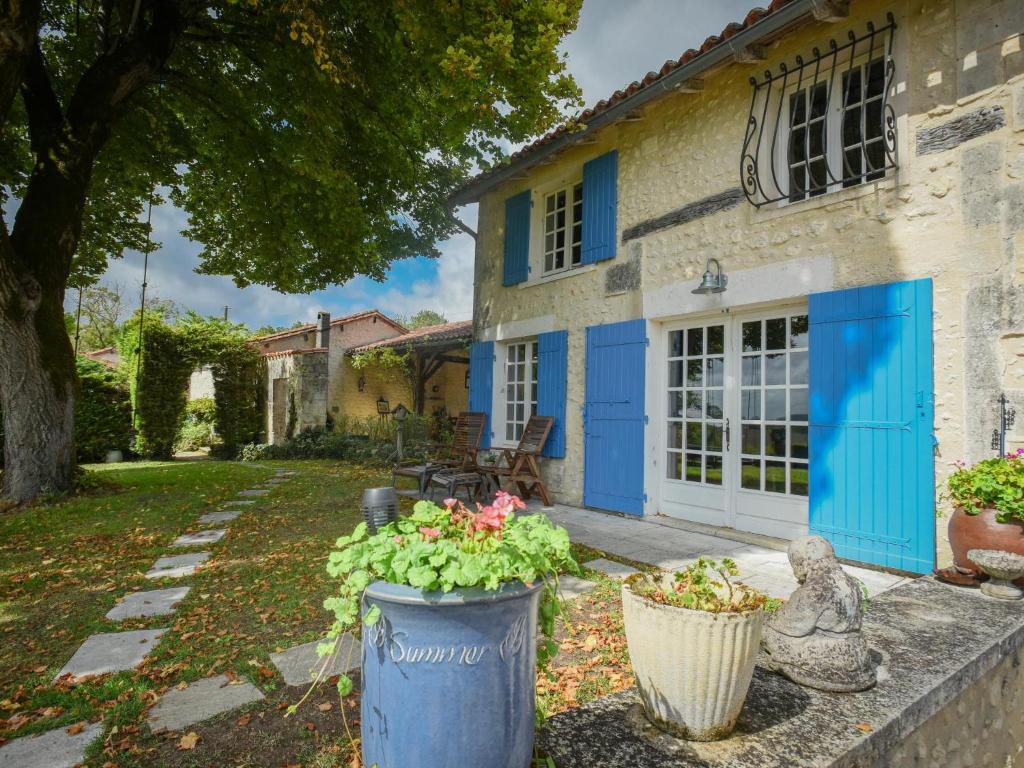 a house with blue doors and flowers in a yard at Maswari en Drapeau in Lusignac