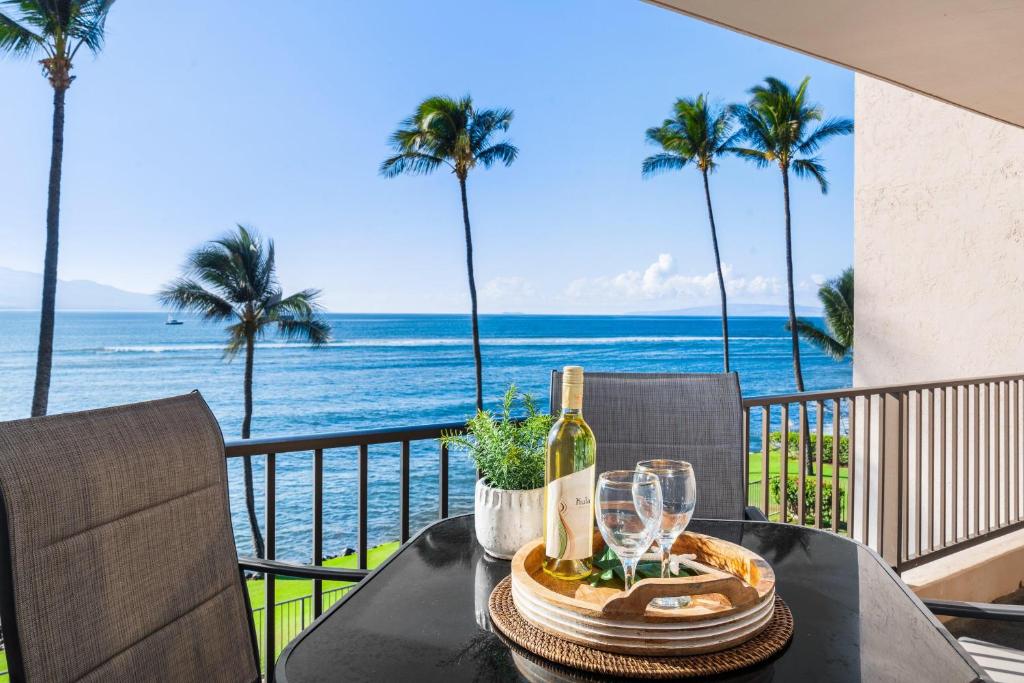 a table with a bottle of wine on a balcony with the ocean at Lauloa 303 in Maalaea