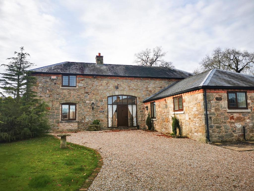 an old stone house with a gravel driveway at Holly Barn in Selattyn