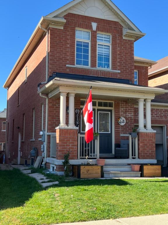 una casa con una bandera canadiense delante de ella en Basement, en Brampton