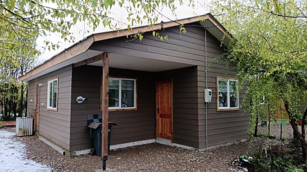 プエルト・アイセンにあるCabaña Moderna en el bosqueの赤い扉の小さな茶色の家