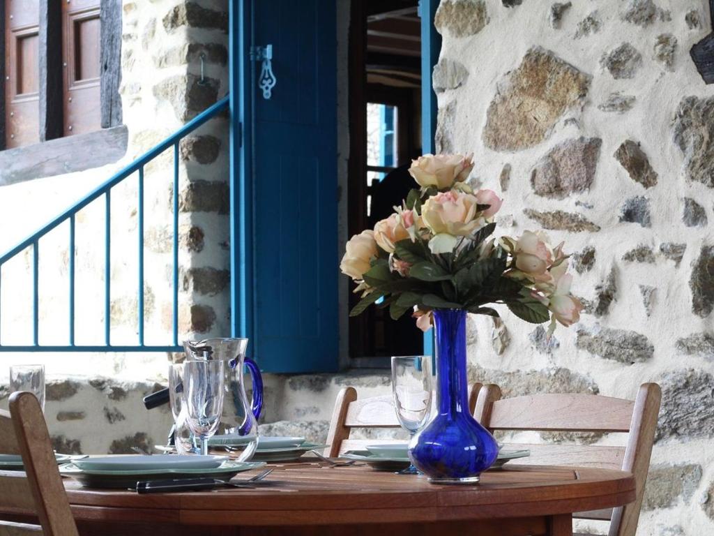 a table with a blue vase with flowers on it at Maison de caractère avec terrasse à 300m de l'Allier, idéale pour pêche, détente et activités familiales - FR-1-582-208 in Villeneuve-dʼAllier