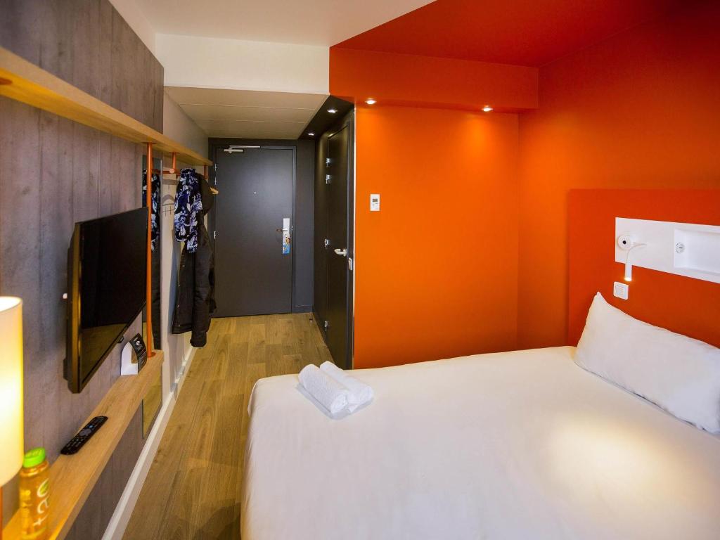 a small room with a bed and a tv at ibis budget Beauvais Aeroport in Beauvais