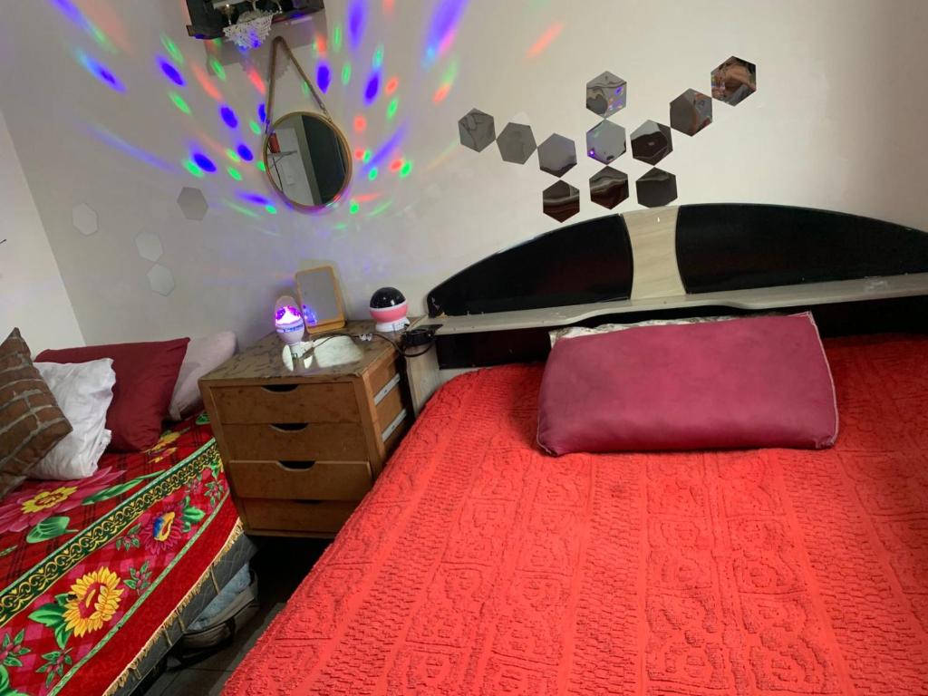 a bedroom with a bed with a red comforter at Pousada Duda Lins in São Vicente