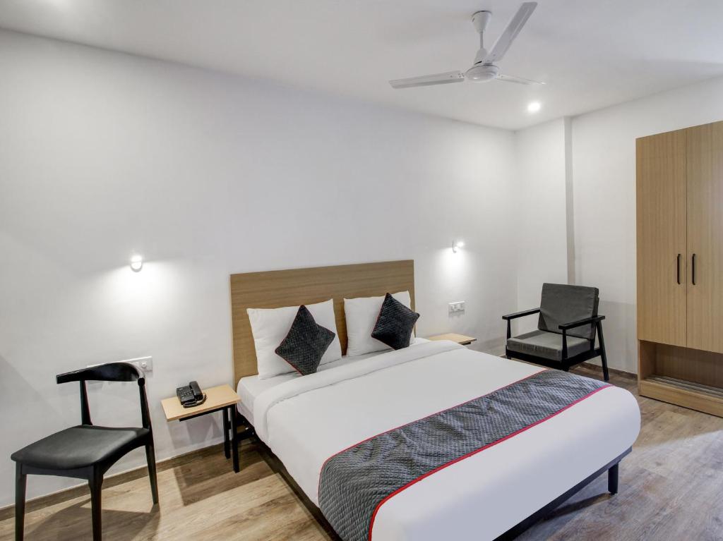 a bedroom with a large bed and two chairs at Super Townhouse RCC Majestic 397 LB Nagar in Hyderabad