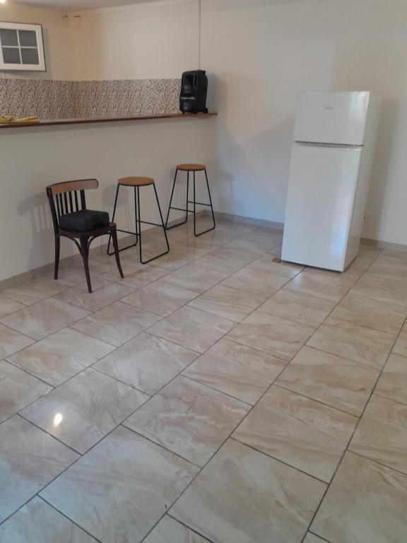 a kitchen with a refrigerator and two chairs on a tile floor at Apparemment à louer au trois ilets en Martinique in Les Trois-Îlets