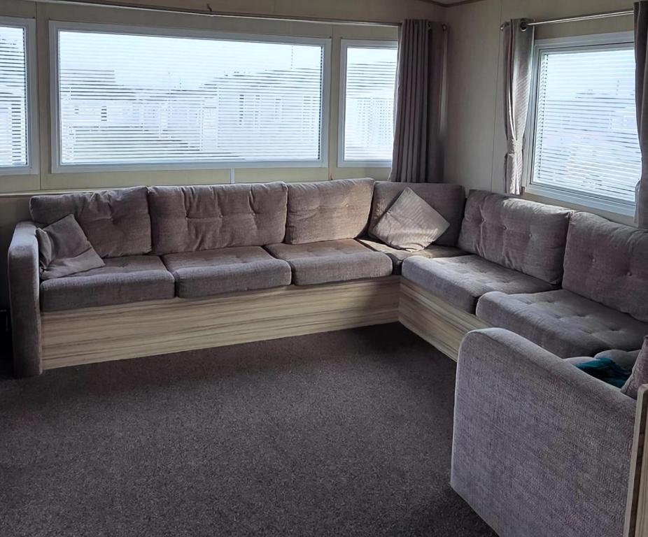 ein großes Sofa im Wohnzimmer mit zwei Fenstern in der Unterkunft Homely 8 Berth Caravan At Harts Holiday Park In Kent Ref 74069B in Leysdown-on-Sea