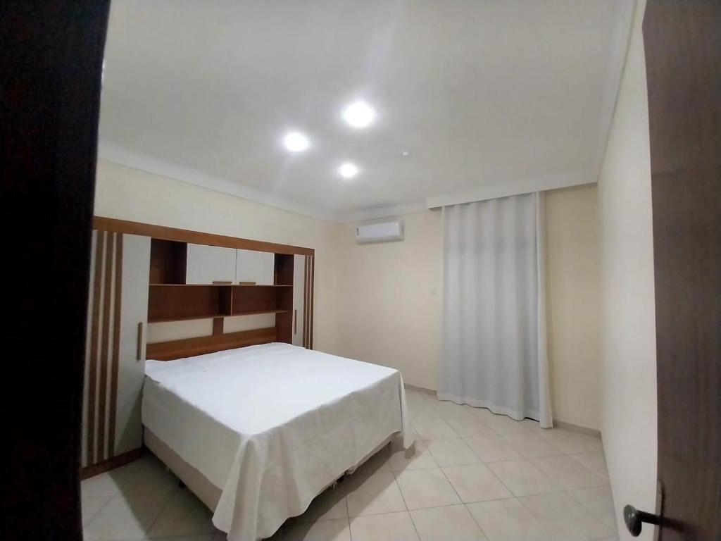 Un dormitorio con una cama blanca en una habitación. en Apartamento próximo avenida São Domingos, en Feira de Santana