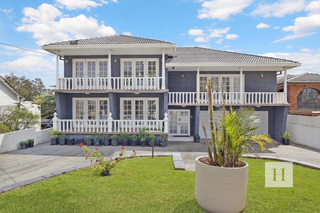 una gran casa azul con un porche blanco en Luxury Waterfront Getaway, en Toukley