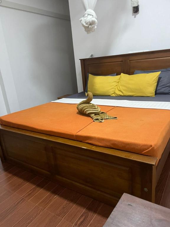 a bed with a wooden frame and yellow pillows at The Ceylan Crest Hotel Ella in Ella