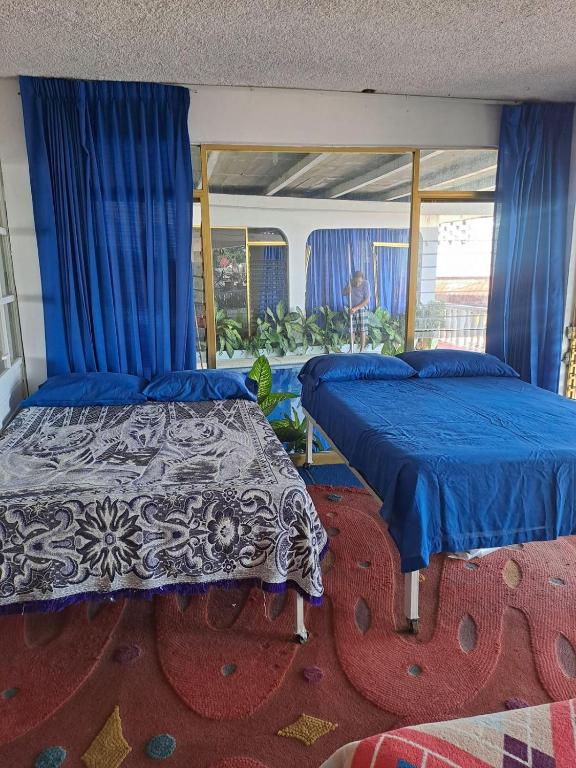 two beds in a room with blue curtains at Casa Vacacional Chula Vista in Acapulco