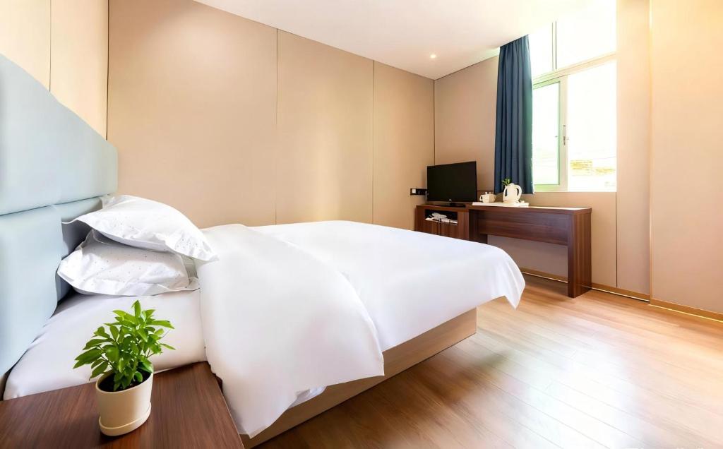 a bedroom with a white bed and a television at Baiyuan Hotel Changgang Baogang Avenue Metro Station Branch in Guangzhou