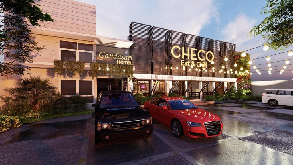 two cars parked in a parking lot in front of a building at Gandasari Hotel in Bandung
