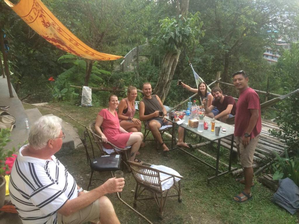 eine Gruppe von Menschen, die um einen Tisch herum sitzen in der Unterkunft Peace guesthouse cottage in Pokhara