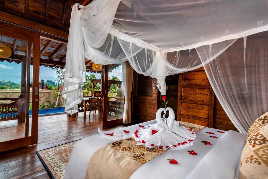 a bedroom with a bed with a canopy at Kamania Villa Ubud by Dhananjaya Hospitality in Tampaksiring