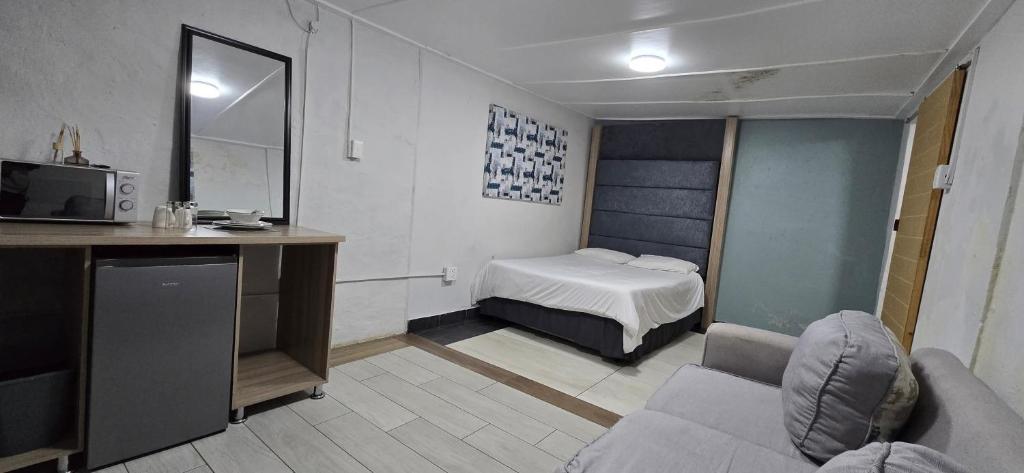 a room with a bed and a couch and a television at Cooper in Potchefstroom