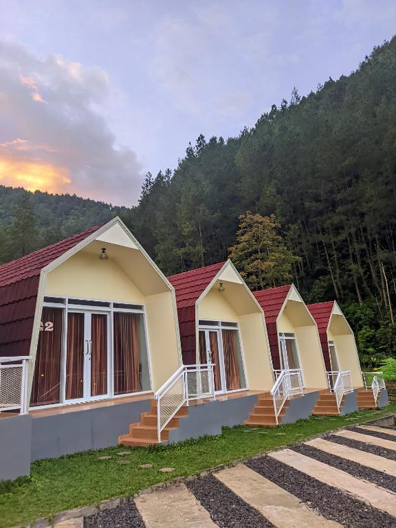 a row of cottages in front of a mountain at Diiza Glamping Tawangmangu in Tawangmangu