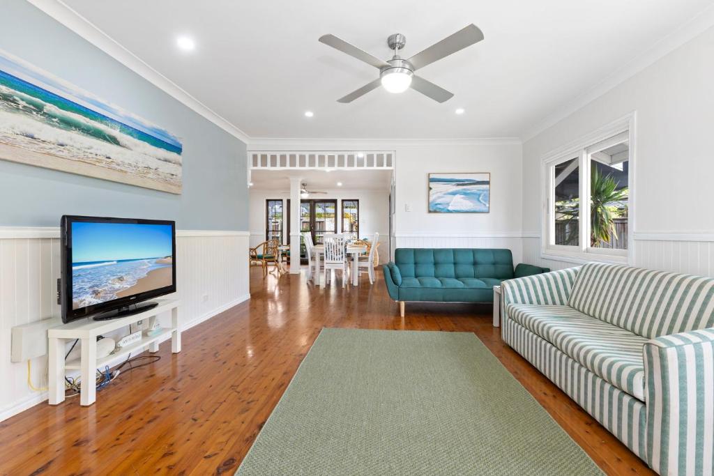 a living room with a couch and a flat screen tv at Seascape Cottage - Shelly Beach in Shelly Beach