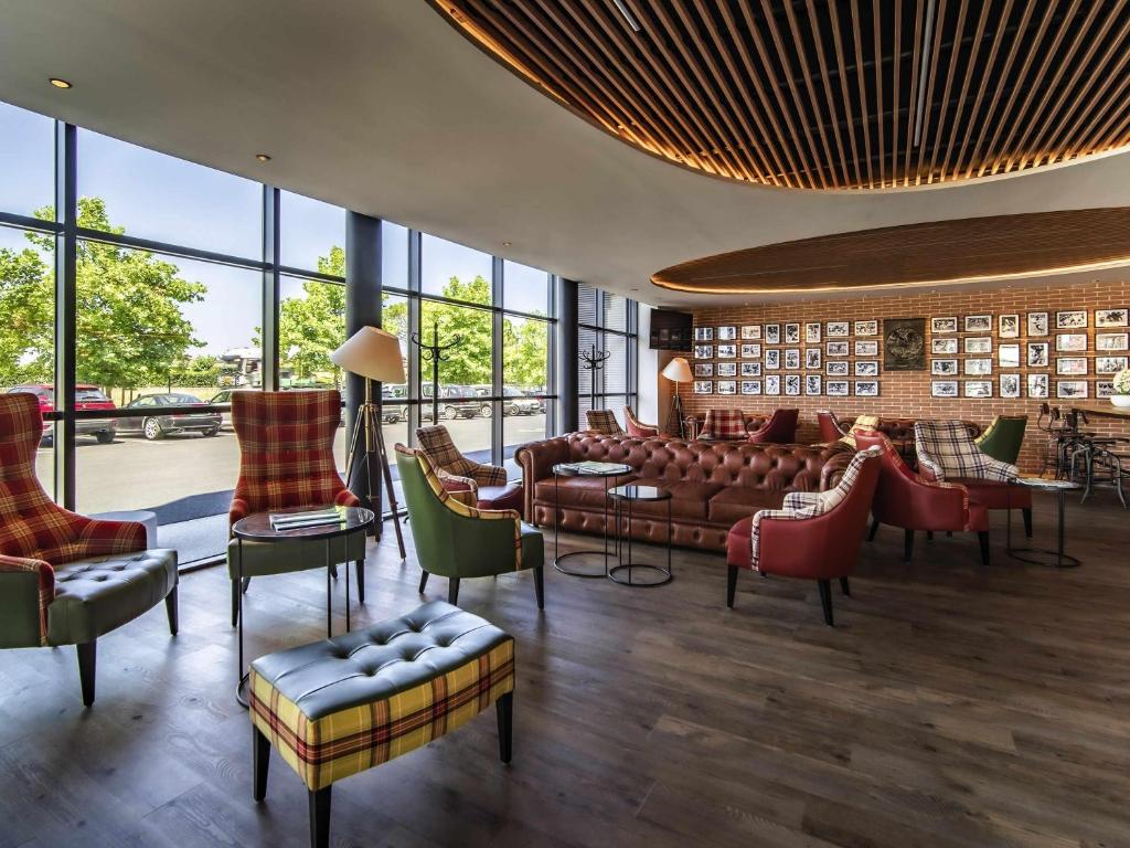 un hall d'entrée avec des canapés, des chaises et des fenêtres dans l'établissement ibis Styles Castelnaudary, à Castelnaudary