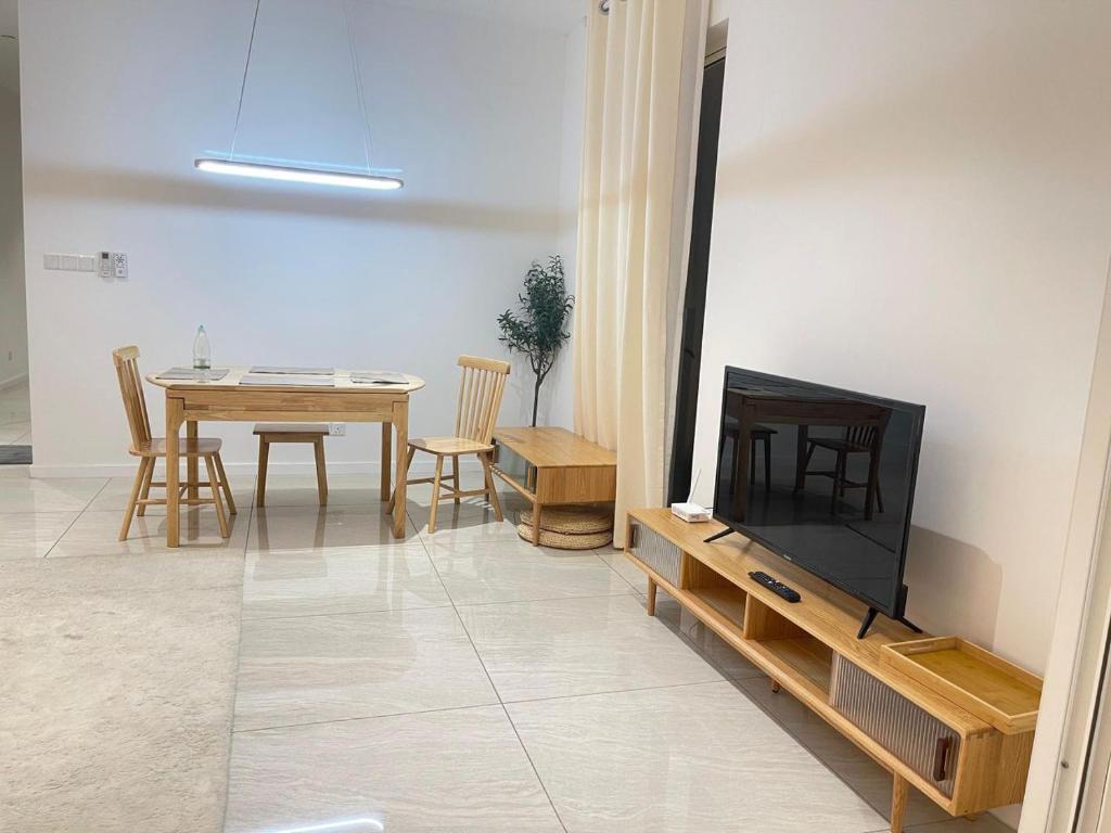 Una sala de estar con un televisor y una mesa con sillas. en Quill Comport Suits KLCC, en Kuala Lumpur