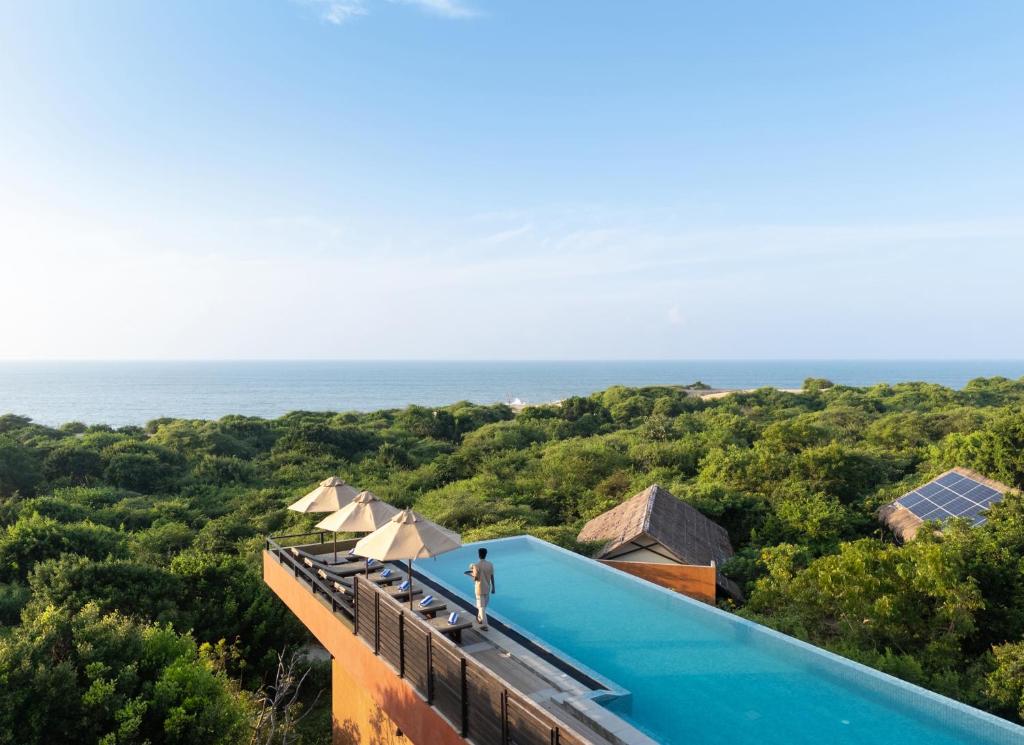 a person standing on the roof of a house with the ocean at Jetwing Jungle Lodge, A Luxury Reserve in Yala