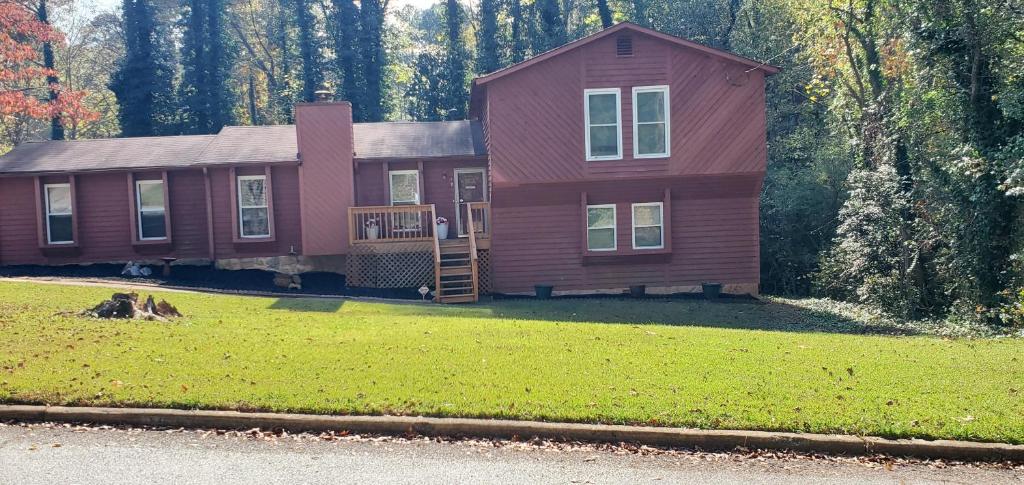 uma grande casa vermelha com uma varanda e um quintal em Humble Abode em Stone Mountain
