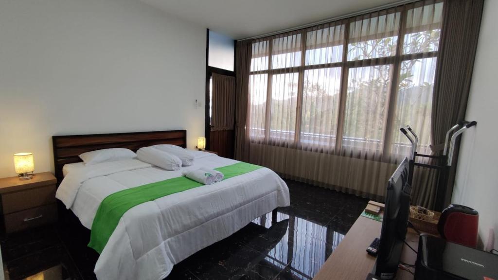 een slaapkamer met een bed en een groot raam bij Menoreh Farm Stay Samigaluh Kulonprogo in Kalirejo