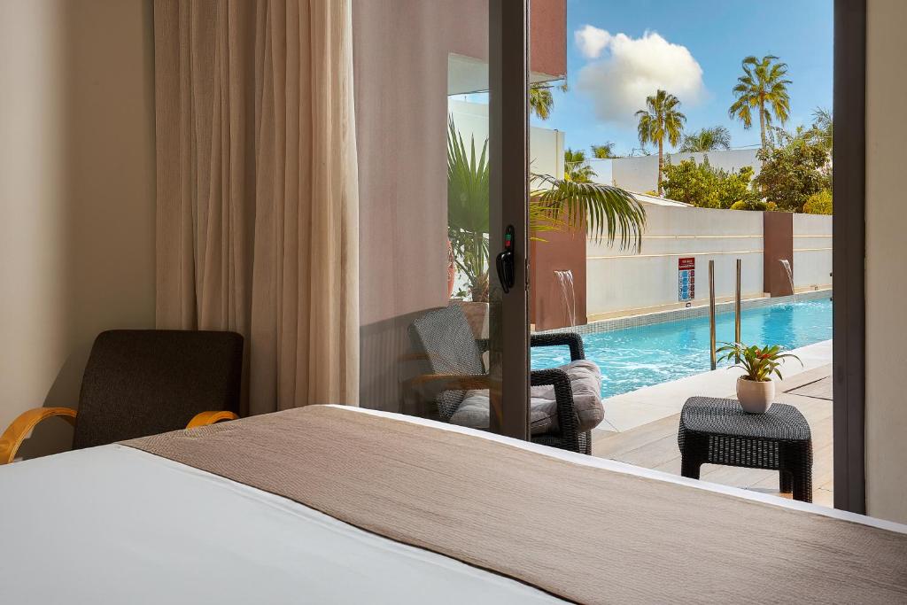 a hotel room with a bed and a swimming pool at Dionisos Hotel in Malia