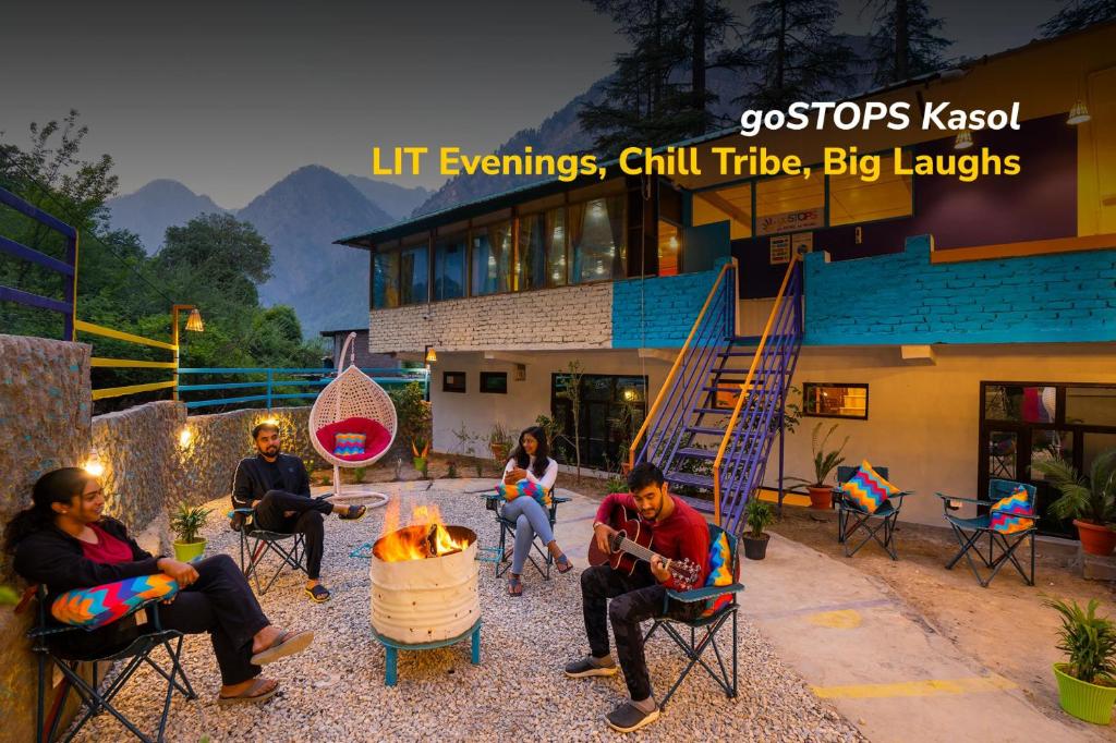 a group of people sitting around a fire in front of a building at goSTOPS Kasol in Kasol