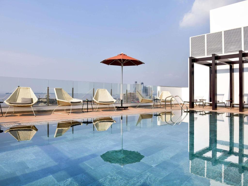a pool with chairs and an umbrella on a building at Novotel Kinshasa La Gombe in Kinshasa