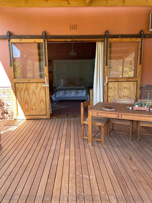 a wooden deck with a bed and a wooden table at Bokmakierie Studio in Montagu
