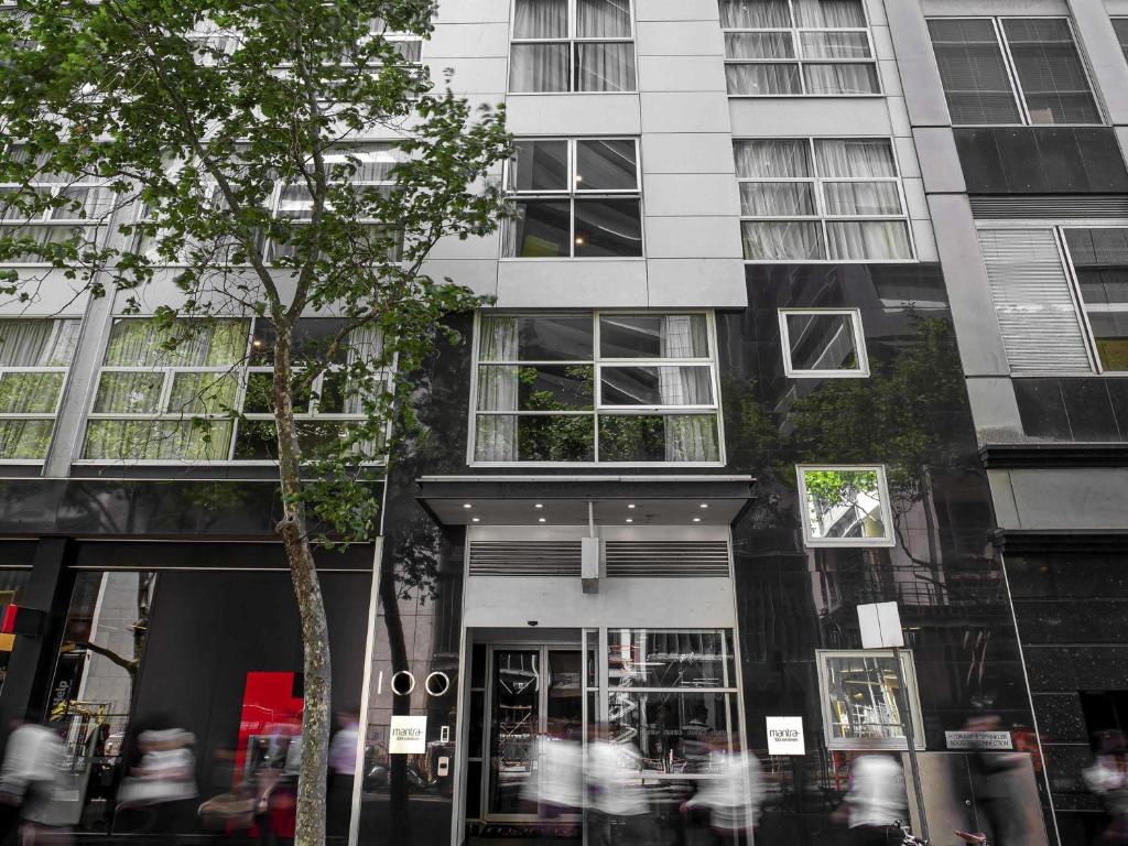 a tall building with people walking in front of it at Mantra 100 Exhibition in Melbourne