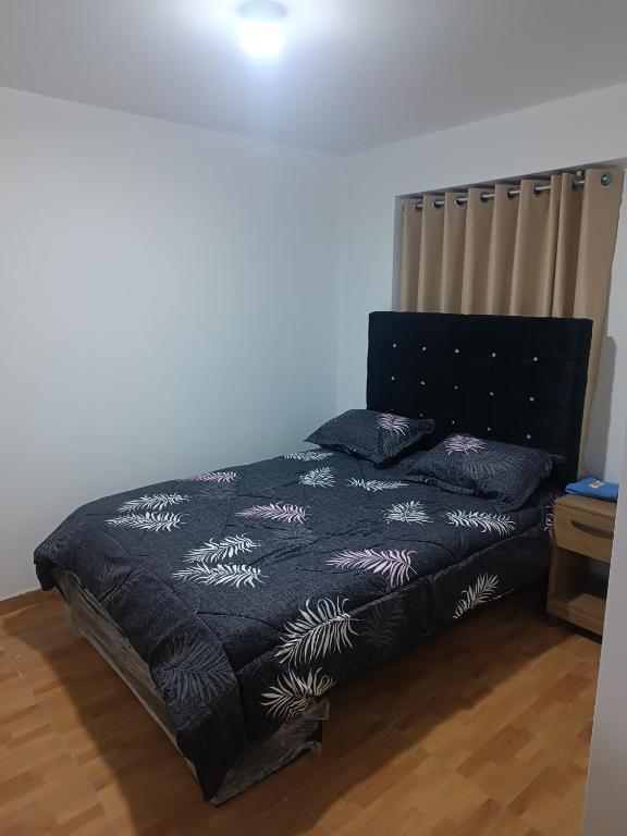 a bedroom with a bed with a black comforter at Hostal JM in Huancayo