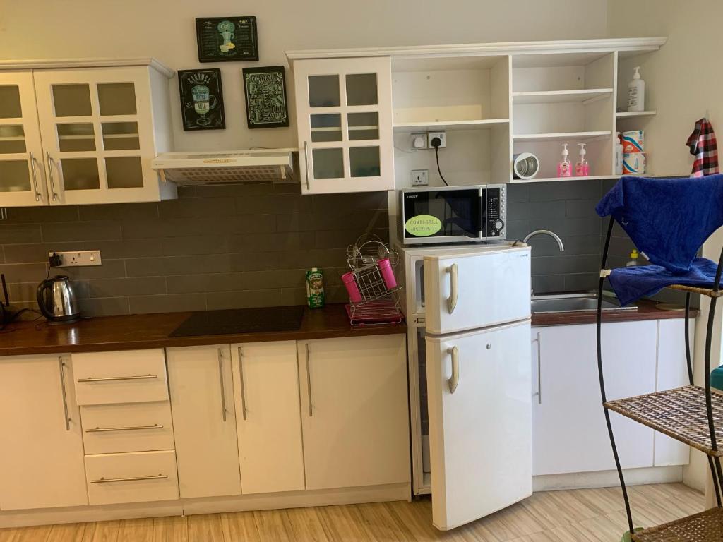 une cuisine avec des armoires blanches et un réfrigérateur blanc dans l'établissement Crown Luxury Apartment 2 Bed Room Apartment, à Colombo