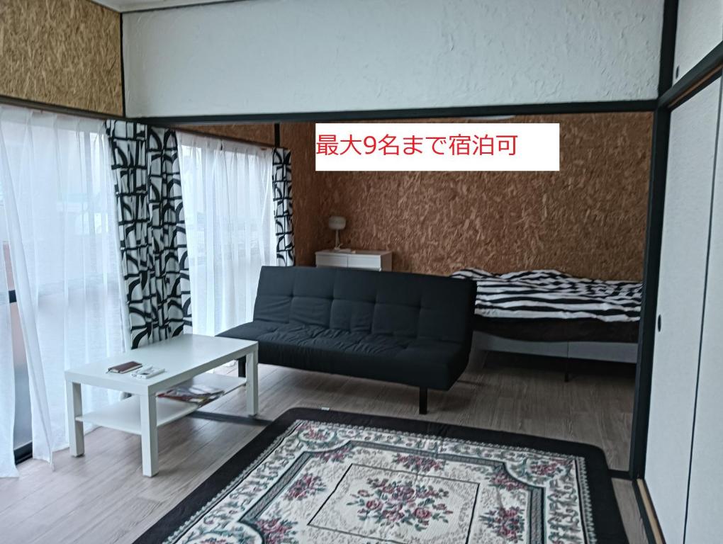 a living room with a couch and a table and a bed at Jupiter 糸島市1棟貸し一長期滞在送迎無料 in Itoshima