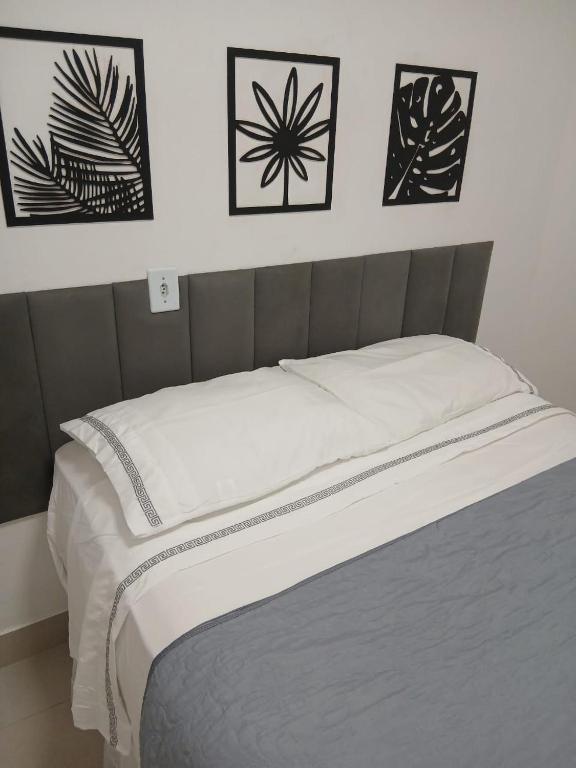 a bed in a bedroom with four pictures on the wall at Apartamento á 1200m da Praia de Itapua in Vila Velha