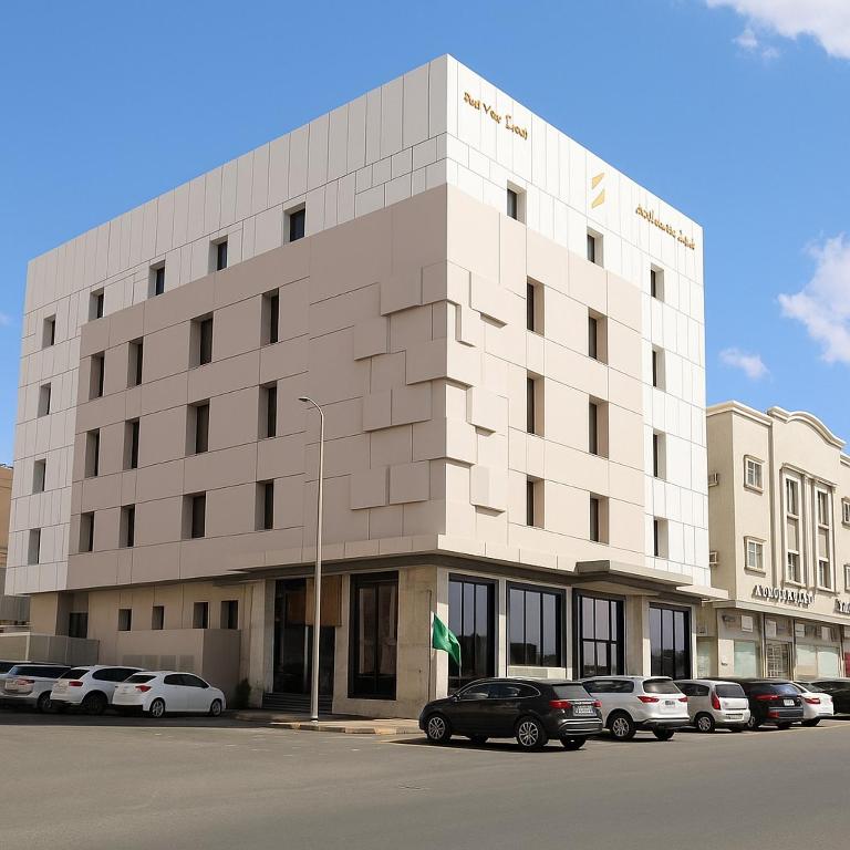 a large white building with cars parked in a parking lot at فندق اطلاله الشمس in Tabuk
