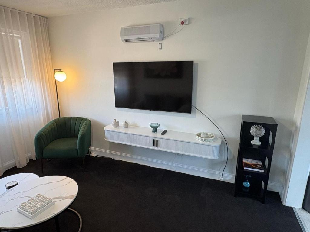 a hotel room with a tv on a wall at Stylish Haven with a Touch of Colour - Hosted by Canstay in Downer