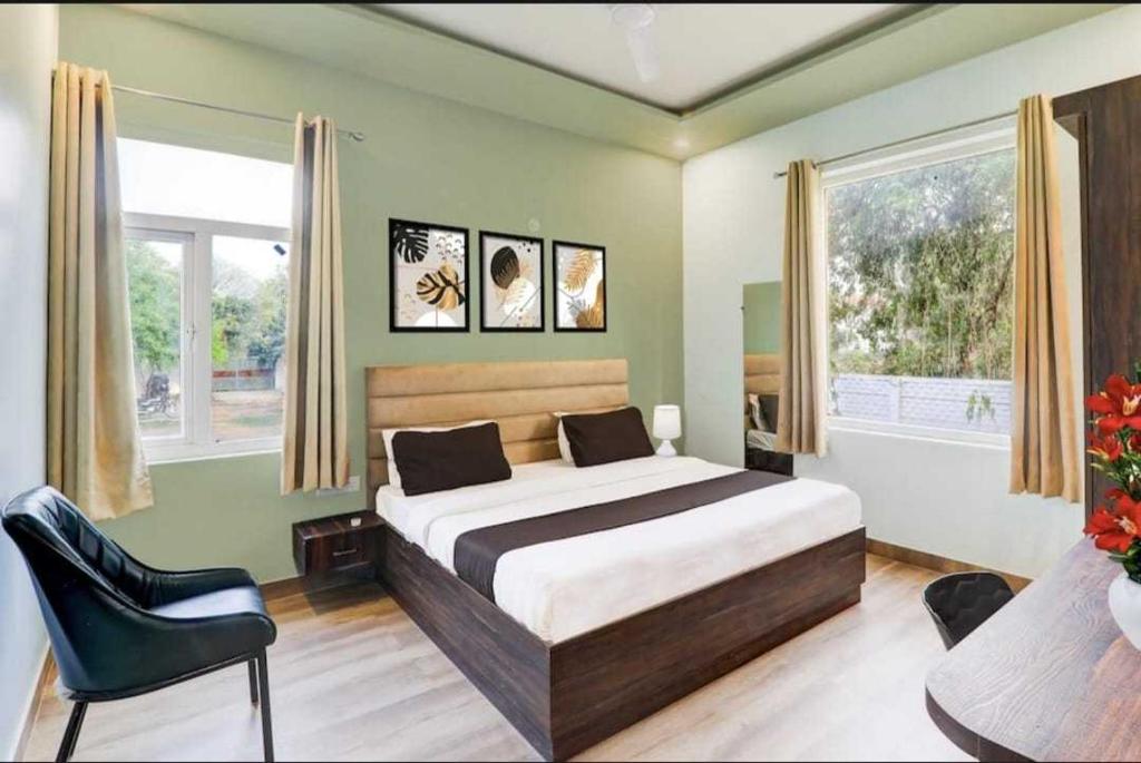 a bedroom with a bed and a chair and windows at Hotel O Sultanpur Railway Junction Formerly Sanskar Marriage Lawan in Sultānpur